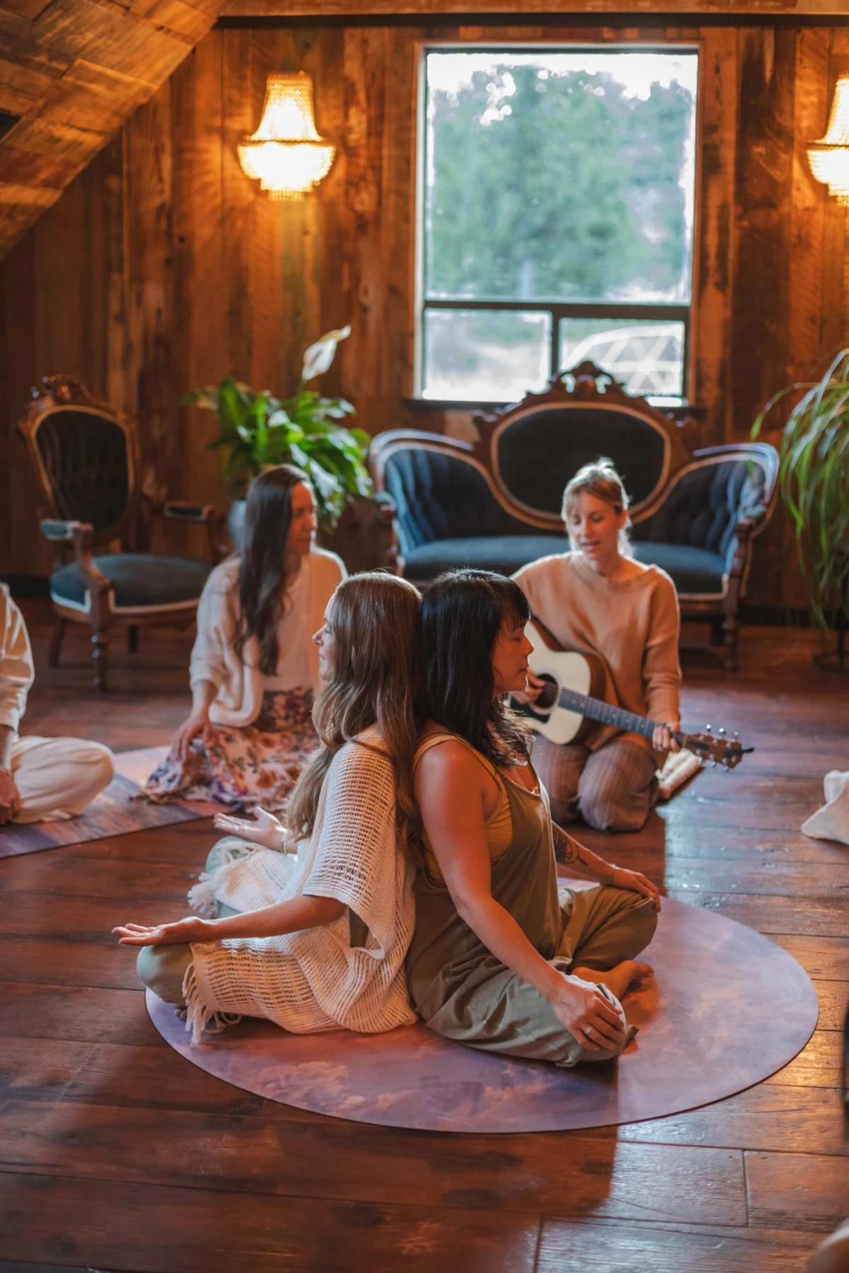 Women sharing embodied song together in a warm wooden room